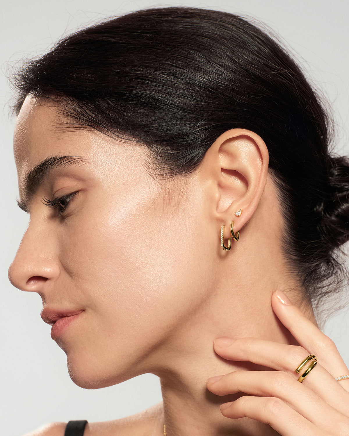 Gold pear stud earrings styled in ear stack with multiple gold earrings