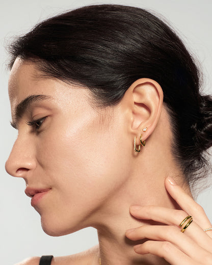 Gold pear stud earrings styled in ear stack with multiple gold earrings